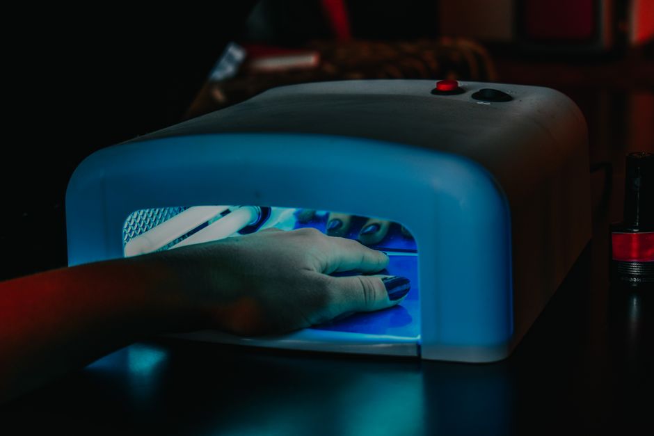 Lampada UV/LED ibrida professionale per unghie con mani inserite durante la polimerizzazione.