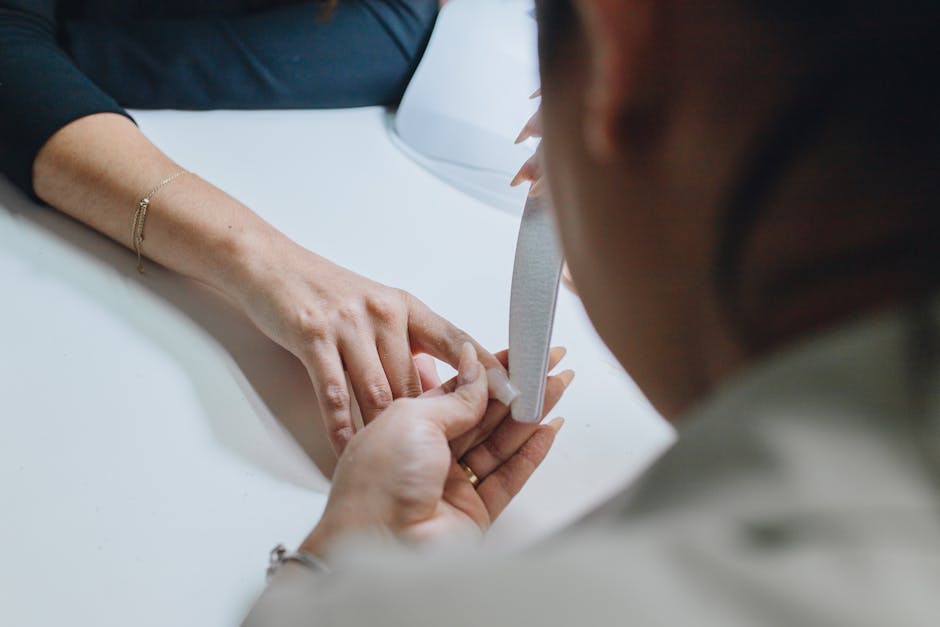 Onicotecnica professionista che lima unghie con precisione, mettendo in evidenza la tecnica e gli strumenti.